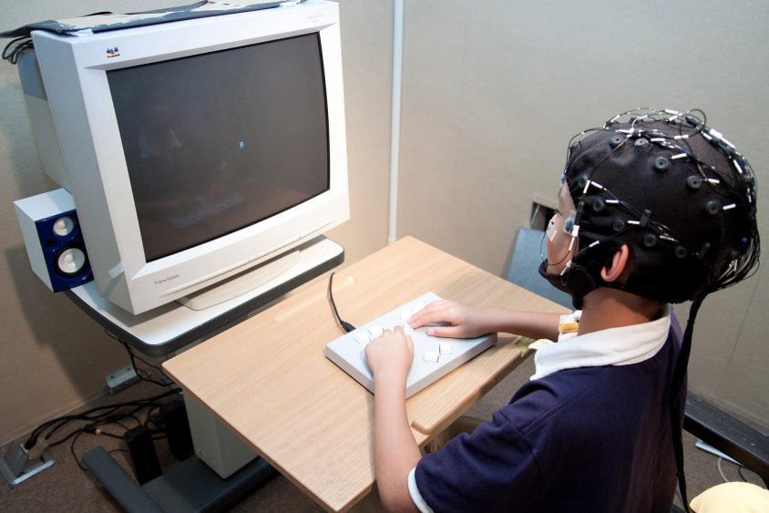 受試者戴著腦波實驗專用帽，看著電腦螢幕按按鍵、或是玩遊戲，藉此收集大腦的反應數據。圖│大腦與語言實驗室