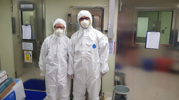 林宜玲實驗室同仁在 P3 實驗室前合影。P3 實驗室的工作人員必須穿著實驗衣，而且穿、脫順序都有嚴格的 SOP，並配合定期訓練。圖│林宜玲