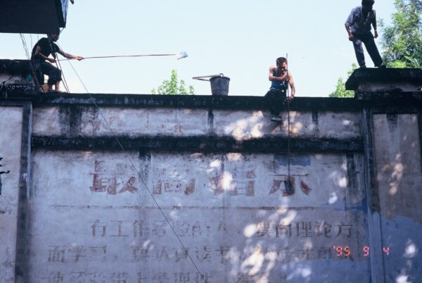 1995 年 9 月 4 日，吳介民與黎安友在四川偏遠小鎮上，卻目睹工人正用白漆抹去牆上的毛語錄，彷彿也見到一個時代的消逝終結。圖│吳介民