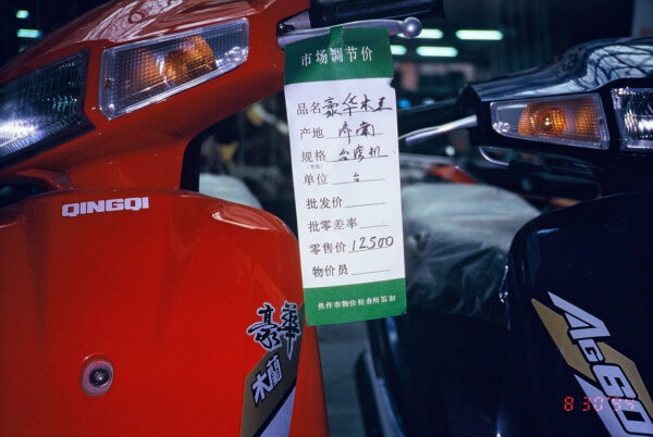 1994 年，河南省濟源市一家摩托車店的標示。明明是當地生產，卻被特別標註「台灣機」，而且一台摩托車要價 12500 元！一方面顯示當時台灣因素扮演的經濟影響力，同時這樣的高價品，必定也是飽賺「灰色收入」的幹部才買得起。圖│吳介民